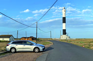 Toyota Corolla next to a lighthouse