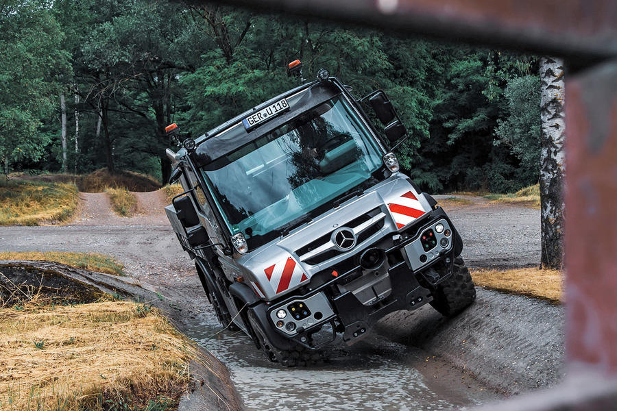 Unimog driving through a deep pool of water on two wheels – front
