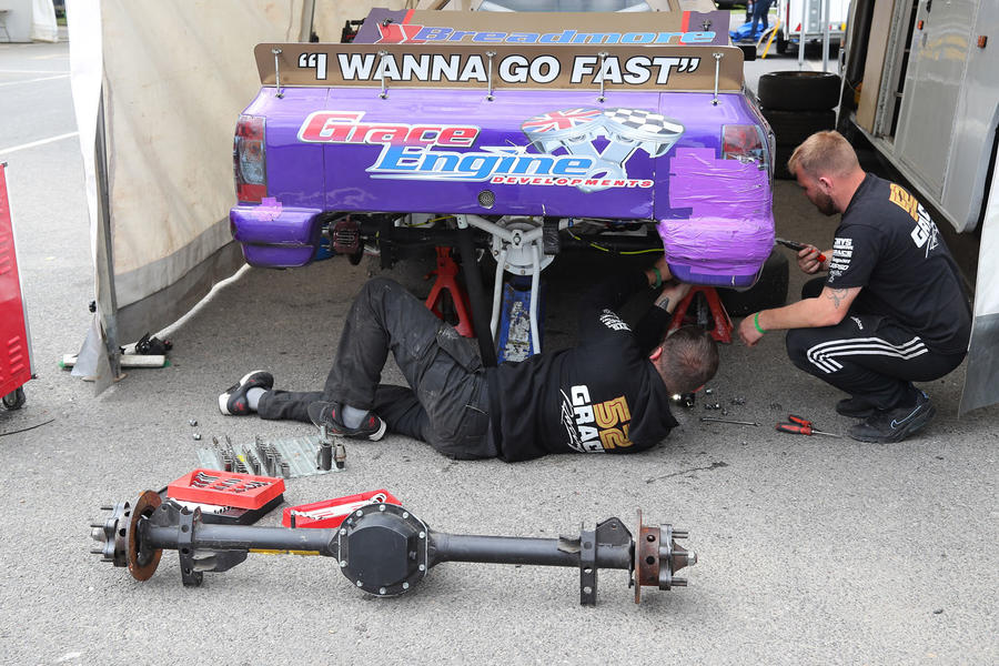Mechanics swap a rear axle on a pick-up racer