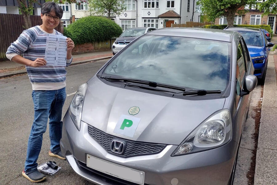Heman Leung stood next to a Honda Jazz with his driving test pass certificate